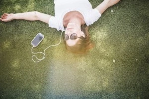 Overhead view of mid adult woman listening to earphones in park